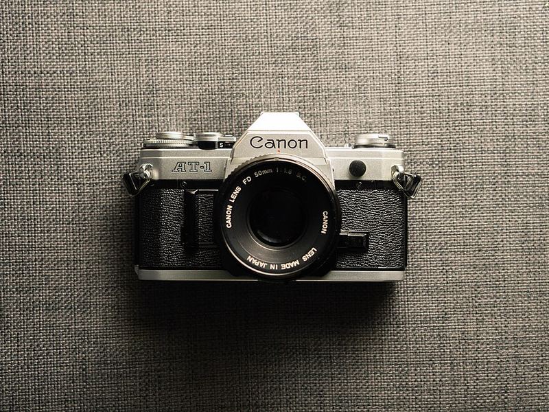 A silver and black Canon AT-1 film camera on a textured background
