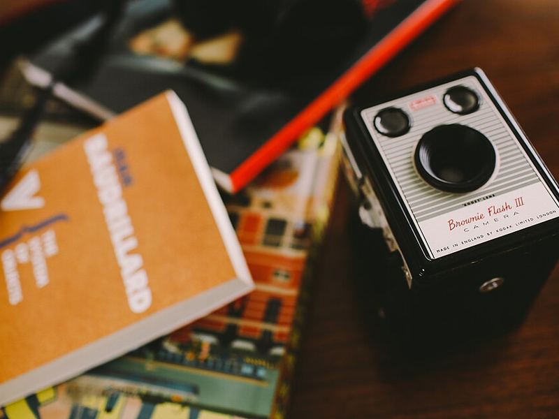 A Kodak box camera on a desk next to an orange book