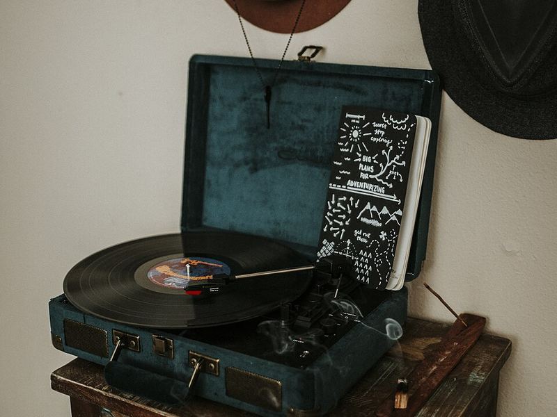 A portable record player in a blue case on a wooden side table