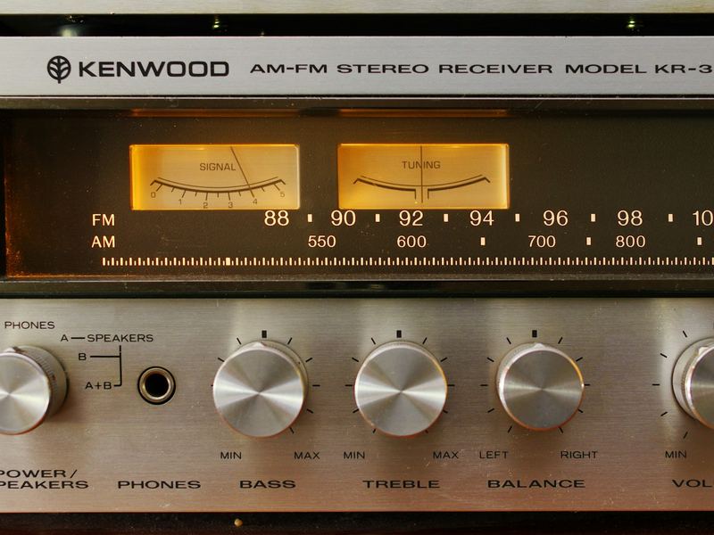 The front panel of a vintage Kenwood stereo receiver with lit dials