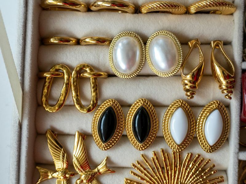 A jewelry box of gold earrings and brooches with pearl and black stones