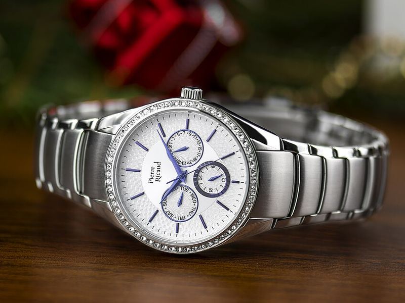 A silver chronograph wristwatch with a white dial on a wooden surface