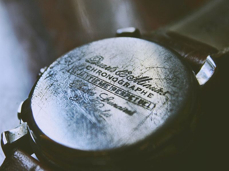 The engraved back of a scuffed vintage wristwatch