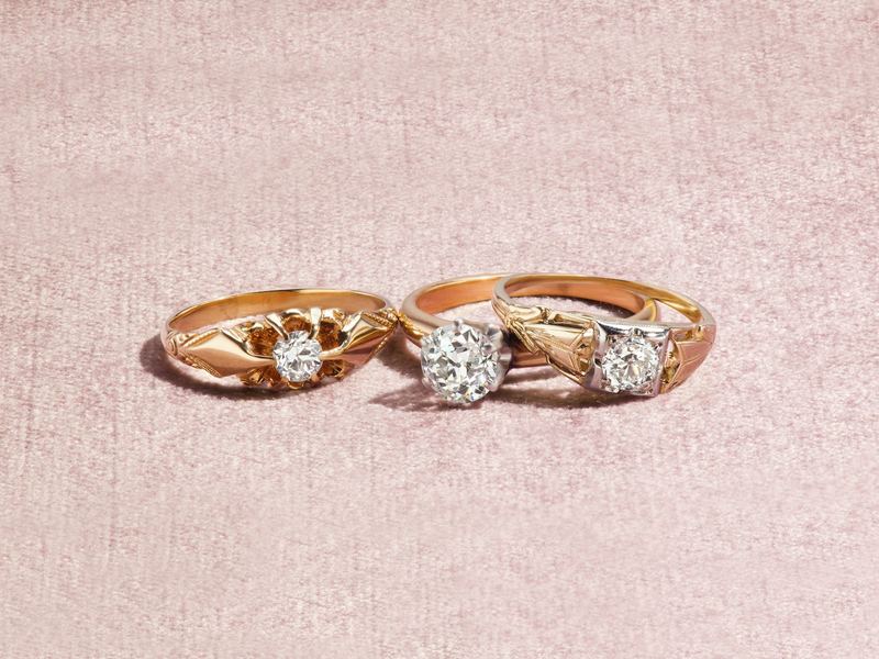 Three vintage gold rings set with stones on a pink cloth