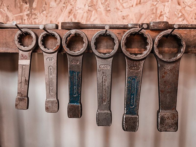 A row of heavy ring wrenches hanging on a wall