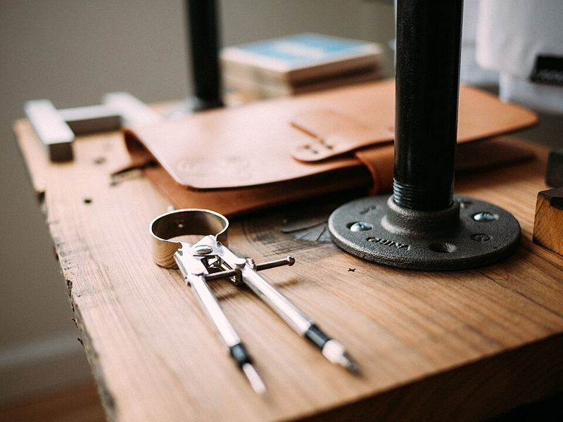 A compass and a leather tool roll on a wooden workbench