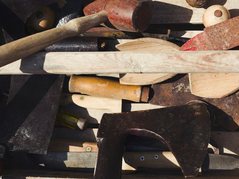 A crate of old woodworking tools with worn wooden handles