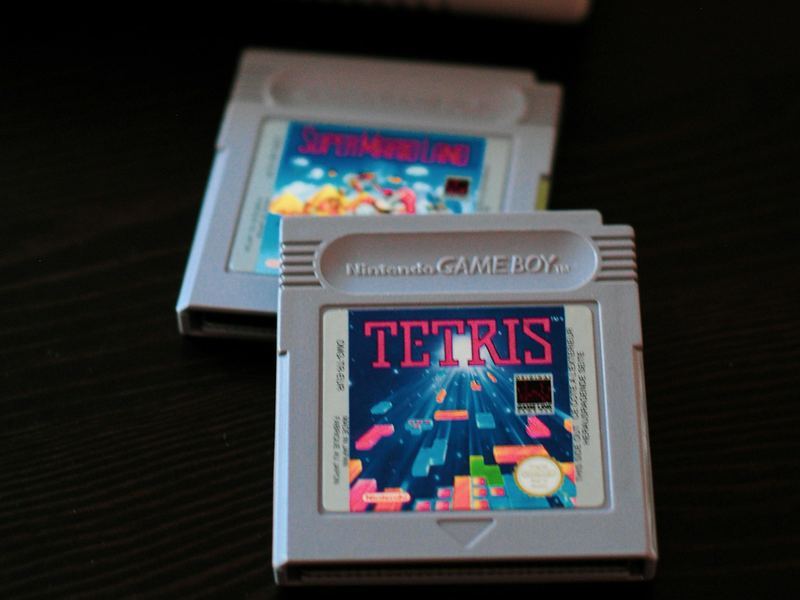 Two Nintendo Game Boy game cartridges, Tetris and Super Mario Land, on a dark table