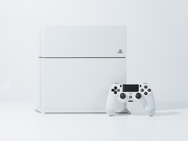 A white PlayStation 4 console with a white controller